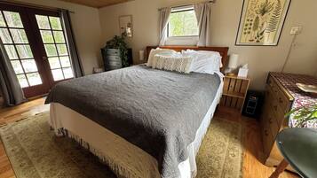 Un dormitorio con una cama grande, un aparador de madera, una silla y una ventana con cortinas.