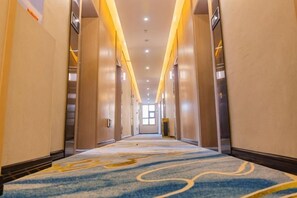 A hotel hallway with a carpeted floor, doors on both sides, and a light fixture on the ceiling. - Minfeng Hotel (Chongqing)