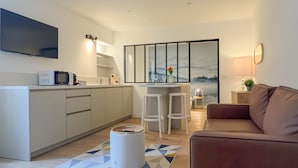 A compact living space with a kitchenette, a flat-screen TV, a sofa, and a dining area with two chairs. - Ushuaia calme rue Carnot (Annecy)