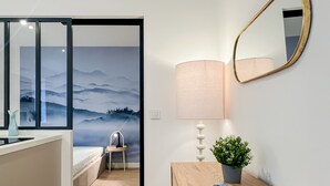 A modern bedroom with a bed, a nightstand, a lamp, a mirror, and a wall with a scenic mural. - Ushuaia calme rue Carnot (Annecy)