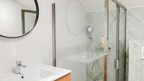 A modern bathroom with a white sink, wooden vanity, a glass shower enclosure, and a mirror. - Ushuaia calme rue Carnot (Annecy)
