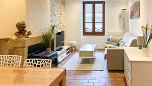 A living room with a fireplace, a sofa, a coffee table, and a TV. - Harmonie en plein cœur du Vieil Annecy (Annecy)