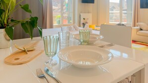 A dining table set with plates, glasses, cutlery, and a wooden board. - Rotonde rue sommeiller (Annecy)
