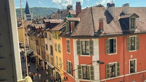 A street view of a town with buildings featuring traditional architecture, a visible shop with a sign, and a clear sky. - Rotonde rue sommeiller (Annecy)