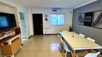 A modern kitchen with a dining area, a TV, and a refrigerator.