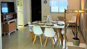 Una sala de estar moderna con comedor, televisor y refrigerador.