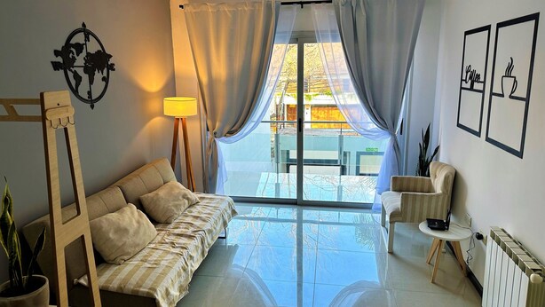 Una sala de estar moderna con un sofá, una mesita, una lámpara y vistas al exterior.