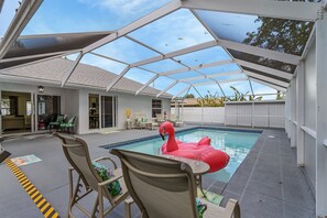 An indoor swimming pool with a glass ceiling, surrounded by lounge chairs and a flamingo float. - Huge 5BR • Heated Pool, BBQ, 3 Suites • Nr Beaches,Pets OK (Naples)
