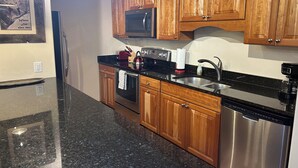 Una cocina con armarios de madera, electrodomésticos de acero inoxidable, encimera de granito y microondas integrado.