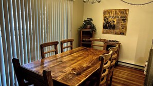 Un comedor con una mesa y sillas de madera, un candelabro y un cartel en la pared.