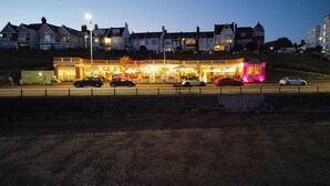 Un hotel muy iluminado con una fila de coches estacionados en la entrada.