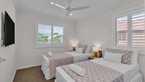 A hotel room with two beds, a ceiling fan, a TV, and a window with blinds. - Sunshine on Saltwater (Kingscliff)