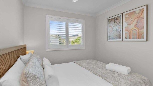 A hotel room with a bed, a window, and two framed artworks on the wall. - Sunshine on Saltwater (Kingscliff)