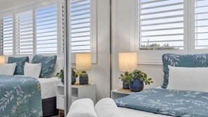 A hotel room with two beds, a window with white shutters, and a view of the sea. - Sunshine on Saltwater (Kingscliff)