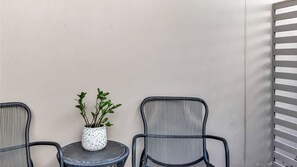 A seating area with two chairs and a small table, a potted plant, and a wall with a slatted design. - Sunshine on Saltwater (Kingscliff)
