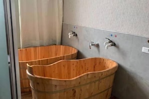 A bathroom with wooden basins and a grey wall with faucets. - New Fali Hotel (Lianjiang)
