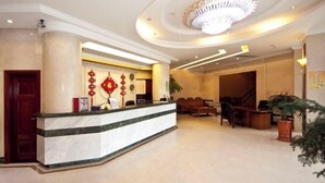 A hotel lobby with a reception desk, seating area, and a staircase leading to another floor. - New Fali Hotel (Lianjiang)