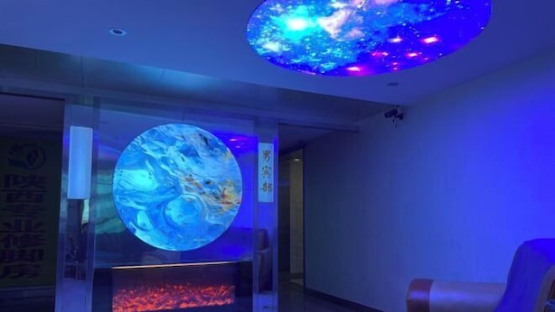 A lobby with a large circular digital display of a blue and white abstract design, a reception desk, and a seating area with a sofa. - New Fali Hotel (Lianjiang)
