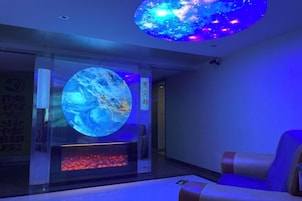 Quarto com uma grande tela digital circular, área de estar e lareira.