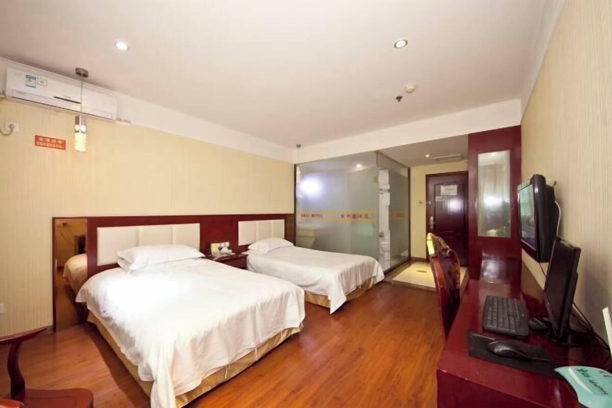A hotel room with two beds, a desk with a computer, and a TV.
