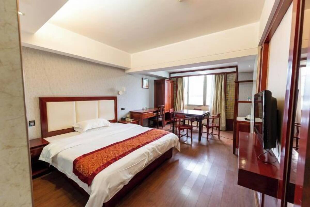 A hotel room with a bed, a desk, and a television.