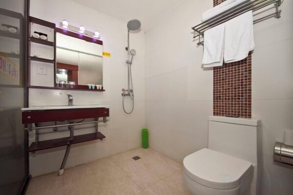 A bathroom with a toilet, sink, mirror, shower, and towel rack.
