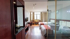 A hotel room with a wooden floor, a bed, a desk with a chair, a TV, and a window with curtains. - New Fali Hotel (Lianjiang)