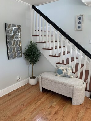 Staircase and bench area with a potted plant and artwork.