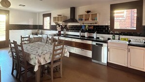 A modern kitchen with a central island, wooden chairs, and a dining table.