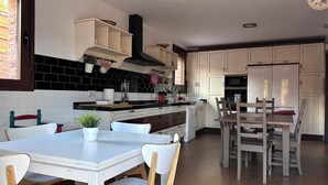 A modern kitchen with white cabinets, a black tiled backsplash, and wooden chairs.