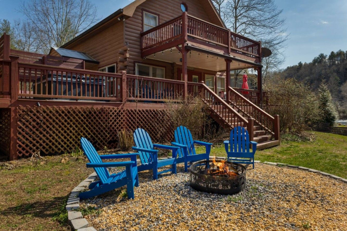 A cabin with a deck, outdoor seating, and a fire pit.