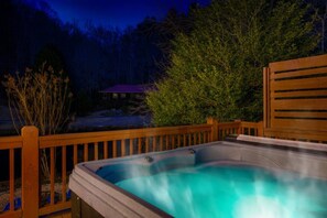 A hot tub on a wooden deck with a view of a house and trees in the background. - kingisher river cabin (Murphy)