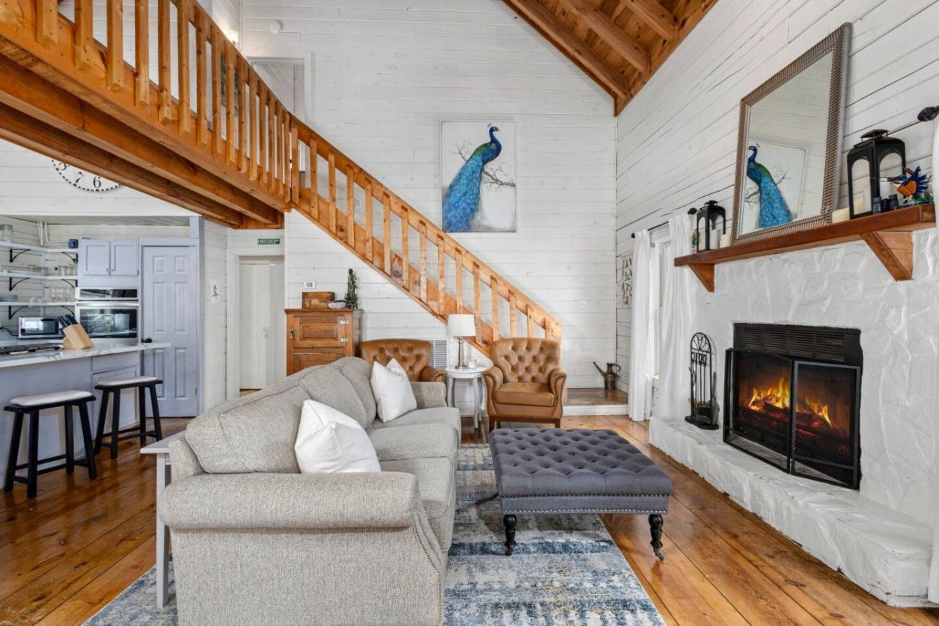 A spacious living room with a fireplace, a staircase, and a kitchen area.