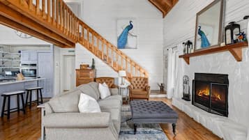 A spacious living room with a fireplace, a staircase, and a kitchen area.