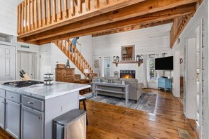 A spacious living area with a fireplace, a kitchen island, and a staircase leading to an upper level. - kingisher river cabin (Murphy)