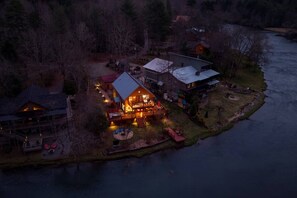 A lakeside property with a main building featuring a large deck and a separate structure with a sloped roof. - kingisher river cabin (Murphy)