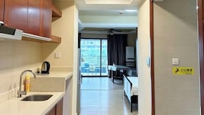 Een keuken met een spoelbak, kasten en een koffiezetapparaat. Er is een eethoek met een tafel en stoelen. Een bordje geeft een babykamer aan.