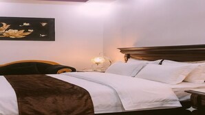 Een hotelkamer met een bed, nachtkastje, lamp en een kunstwerk aan de muur.