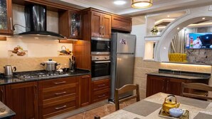 Een moderne keuken met houten kastjes, een roestvrijstalen koelkast en een eethoek met een tafel voor twee personen.