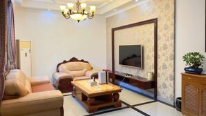 A living room with a sofa, a coffee table, a TV, and a chandelier. - Hewu Bay Farmhouse (Shanghai)