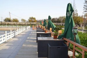 A deck with outdoor seating, a railing, and potted plants. - Hewu Bay Farmhouse (Shanghai)