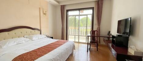 A hotel room with a large bed, a desk with a television, and a balcony with curtains.