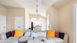 Una sala de estar moderna con un sofá modular, un reposapiés y un control remoto sobre este.