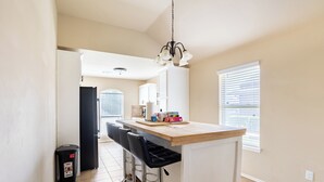 Una cocina con barra, un cubo de basura y un refrigerador.