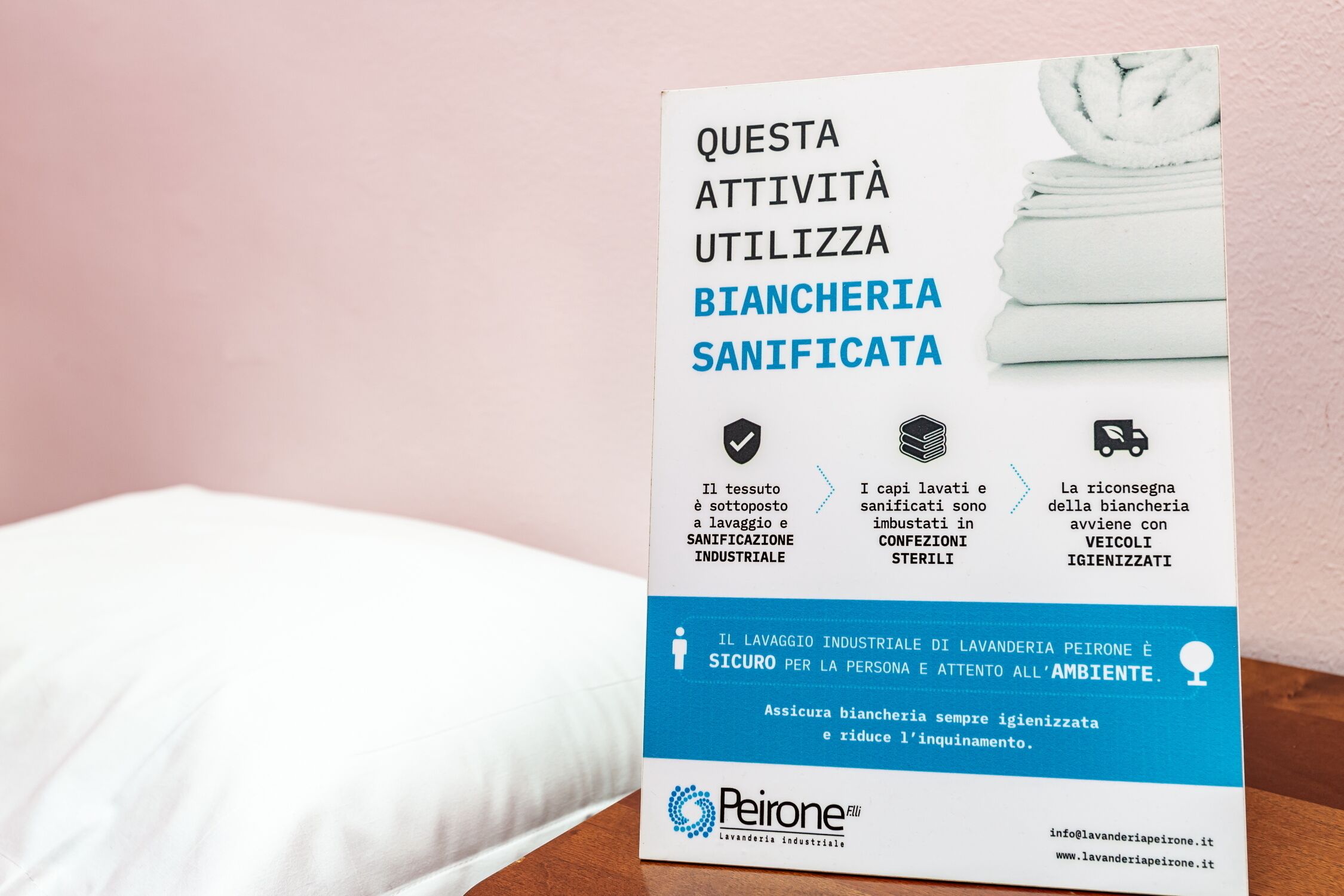 Una confezione di detersivo Peirone con etichetta blu e bianca, posizionata su una superficie di legno davanti a una parete rosa.