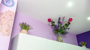 Un bany amb una paret morada, un armari blanc i un ram de flors.