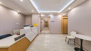A hotel reception area with a marble reception desk, a waiting area with chairs, and a hallway leading to other rooms. - F1 Business Hotel (Shanghai Xinhua Hospital) (Shanghai)