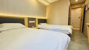 A hotel room with two beds, a nightstand, and a wardrobe.