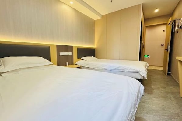A hotel room with two beds, a nightstand, and a wardrobe. - F1 Business Hotel (Shanghai Xinhua Hospital) (Shanghai)