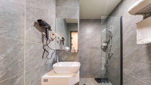 A modern bathroom with a white vessel sink, a glass-enclosed shower, and a hairdryer mounted on the wall. - F1 Business Hotel (Shanghai Xinhua Hospital) (Shanghai)